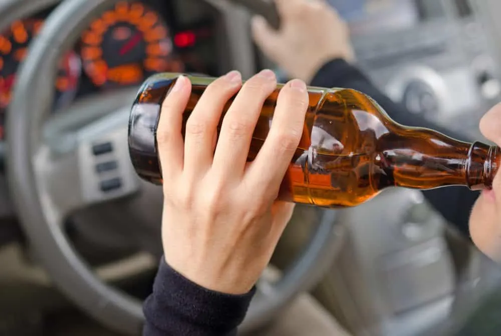 Motorista dirigindo com bebida alcoólica, ilustrando situação sujeita à multa por embriaguez